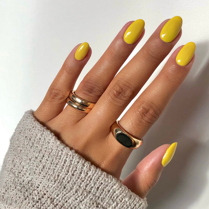 Limoncello yellow nail polish manicure on a medium skin tone with gold rings