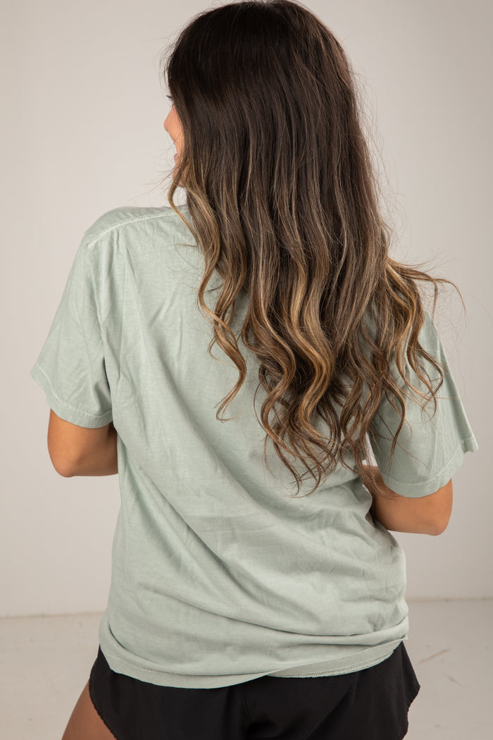 Woman wearing a light green t-shirt with a plain background