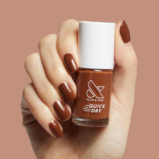 Hand holding Olive and June Americano quick dry polish in rich coffee brown for a bold at home mani look