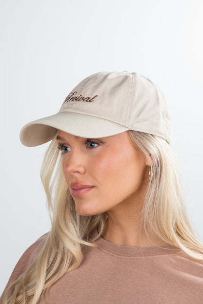 Woman wearing a beige cap with 'Revival' text on a white background