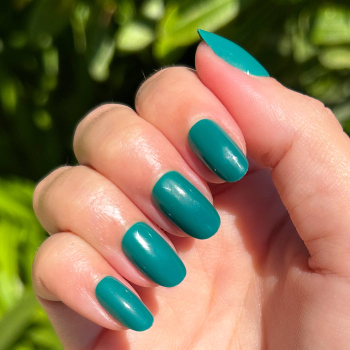 Besties - Press-On | Short | Round showing hand with smooth bright teal short round press-on manicure outdoors in natural sunlight