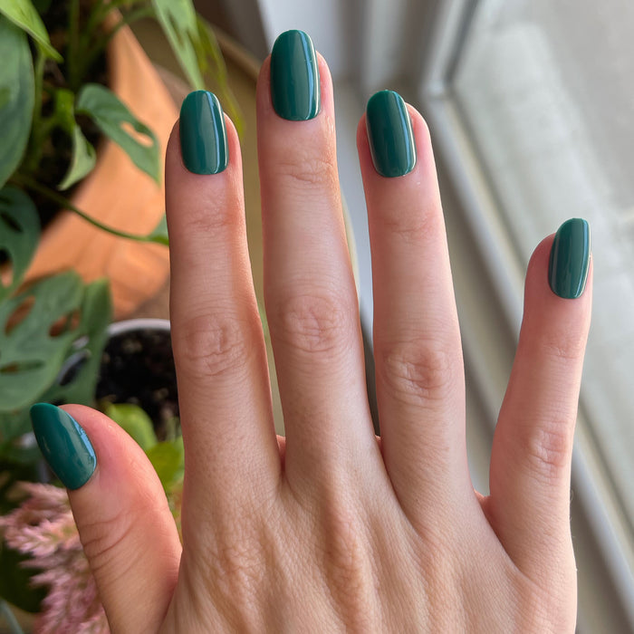 Besties - Press-On | Short | Round showing hand with glossy deep emerald green short round press-on manicure indoors near window light
