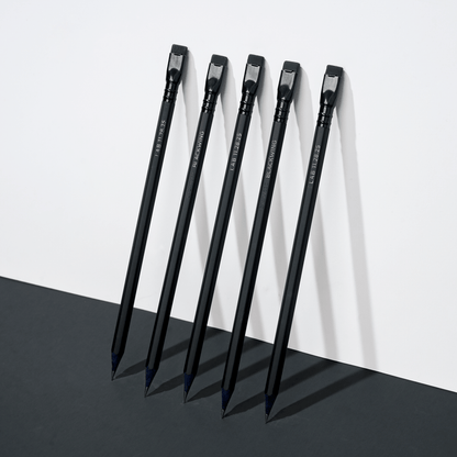five black pencils leaning against a white wall