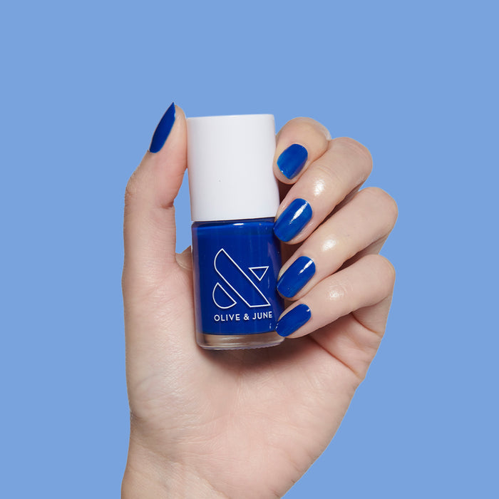 Blueberry Muffin cobalt blue nail polish on neatly manicured nails held against matching blue background