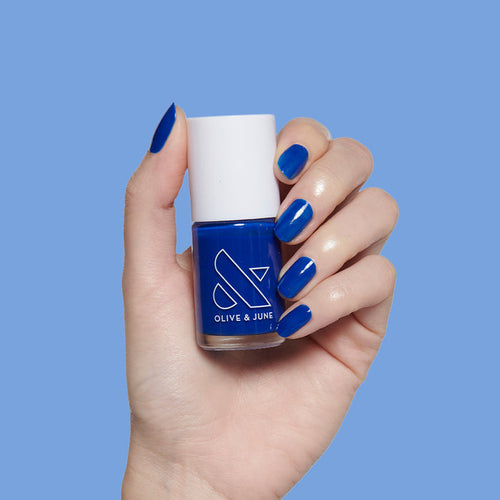 Blueberry Muffin cobalt blue nail polish on neatly manicured nails held against matching blue background