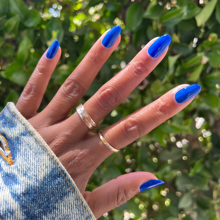 Medium-length almond-shaped nails polished with Blueberry Muffin cobalt blue long-lasting nail polish outdoors