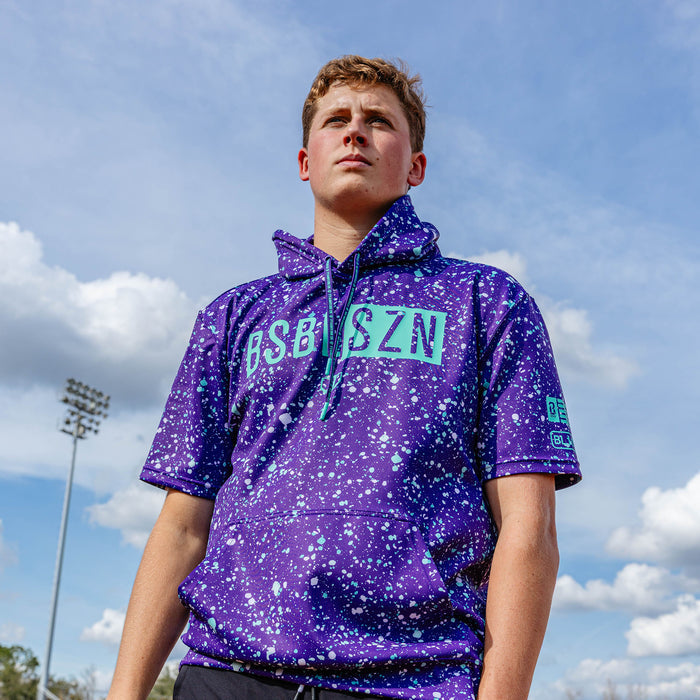 Adult model wearing splatter purple and teal BSBL-SZN short sleeve hoodie