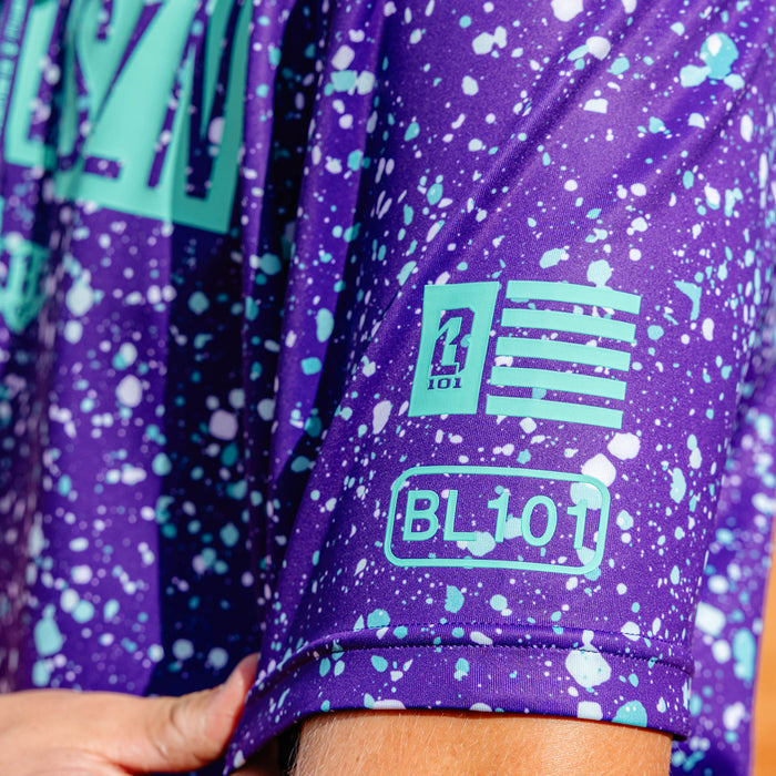 Adult model wearing splatter purple and teal BSBL-SZN short sleeve hoodie