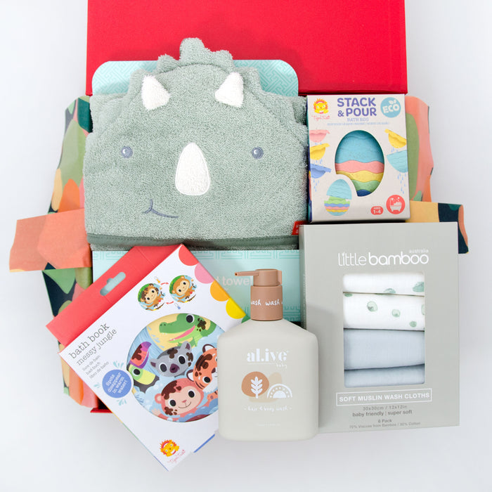 A baby hamper gift set presented in a red box, including a dinosaur hooded towel, bath toys, a bath book, and a bottle of hair and body wash. Price: 135