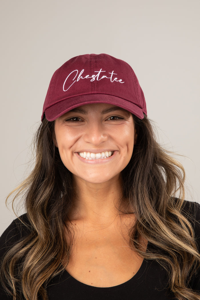 Woman wearing a maroon cap with 'Chestate' text on a plain background
