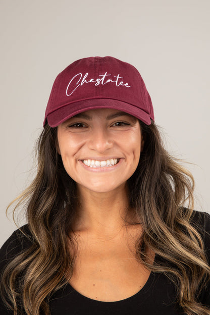 Woman wearing a maroon cap with 'Chestate' text on a plain background