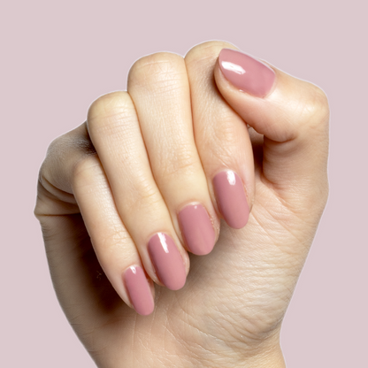 Hand with light skin tone wearing Can I Borrow A Sweater? mauve gel polish manicure against soft mauve background