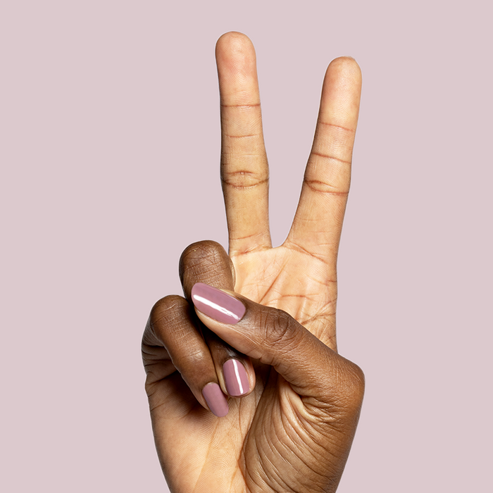Hand with dark brown skin showing glossy mauve gel polish manicure in Can I Borrow A Sweater? shade against soft mauve background