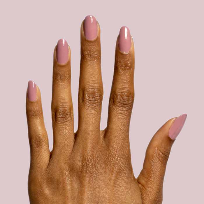 Hand with deep skin tone wearing Can I Borrow A Sweater? gel polish manicure against soft pink background