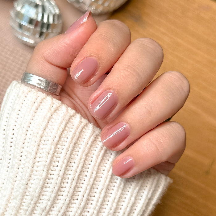 Hand with light skin tone wearing Can I Borrow A Sweater? glossy gel polish manicure over cozy sweater sleeve