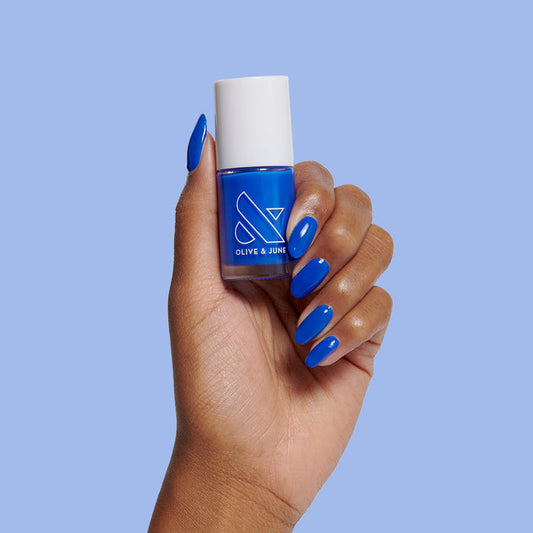 Hand with glossy bright blue Can’t Lose nail polish for a smooth, long-lasting mani by Olive and June