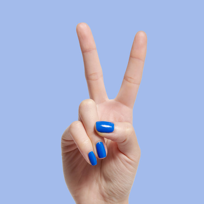 Hand with short nails polished in bright jersey blue Can’t Lose for a smooth, long-lasting manicure by Olive and June
