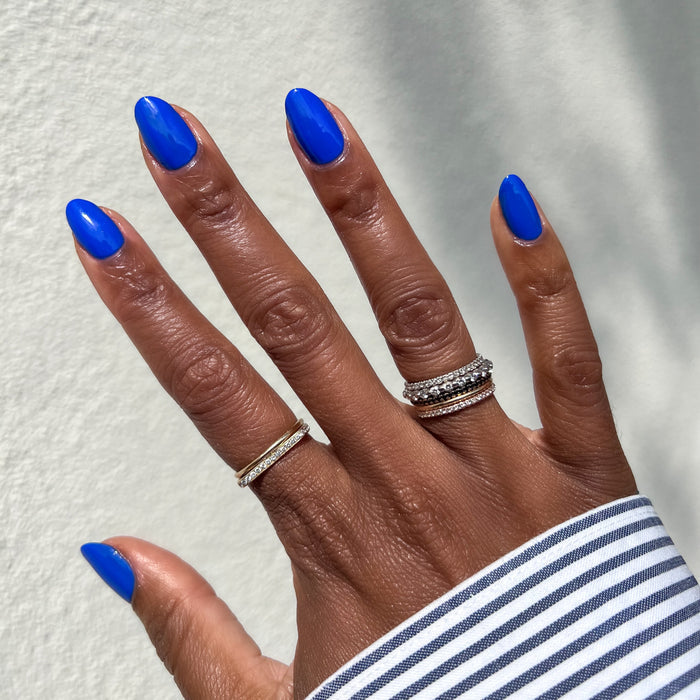 Hand with almond-shaped nails polished in bright Can’t Lose jersey blue for a smooth, long-lasting manicure by Olive and June