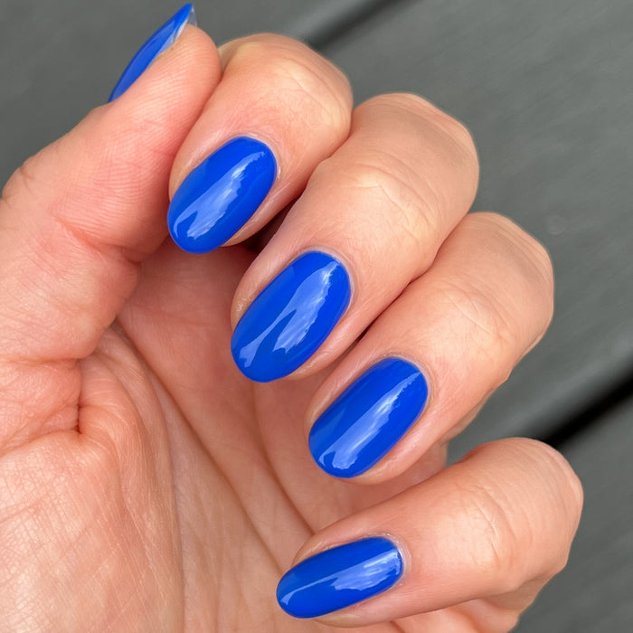 Hand with glossy, rounded nails in bright Can’t Lose blue for a smooth, long-lasting manicure by Olive and June