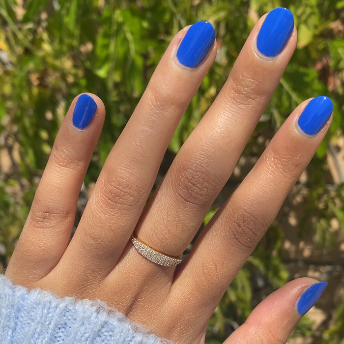 Hand with short nails painted in bright jersey blue Can’t Lose nail polish for a smooth, long-lasting mani by Olive and June