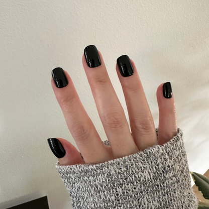 Cateye | Extra Short | Squoval - Tab Press-On nails in glossy inky black shown on hand with cozy sweater background