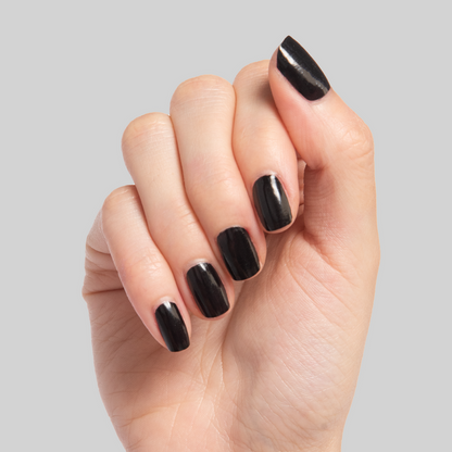 Close-up of hand with shiny black Cateye nail polish on nails against a neutral background for a sleek mani look