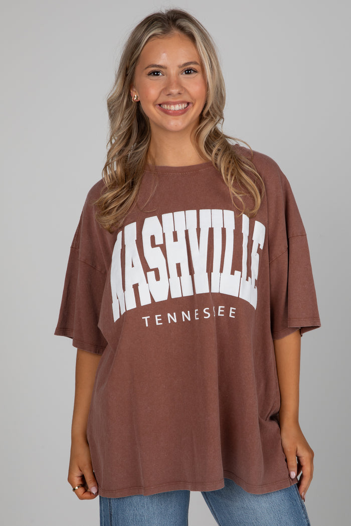 Woman wearing a brown t-shirt with 'Nashville Tennessee' text on a gray background