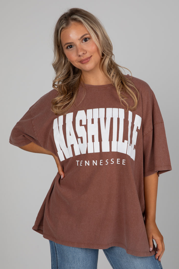 Woman wearing a brown t-shirt with 'Nashville Tennessee' text on a gray background