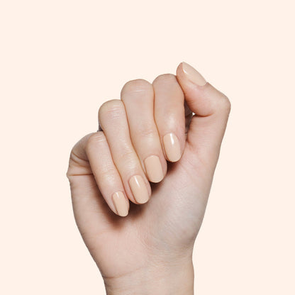 Hand with glossy Coffee Milk neutral tan nail polish on medium-length nails against light background