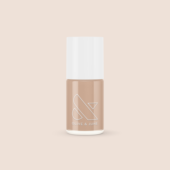 Bottle of Coffee Milk nail polish in creamy neutral tan shade by Olive and June on beige background