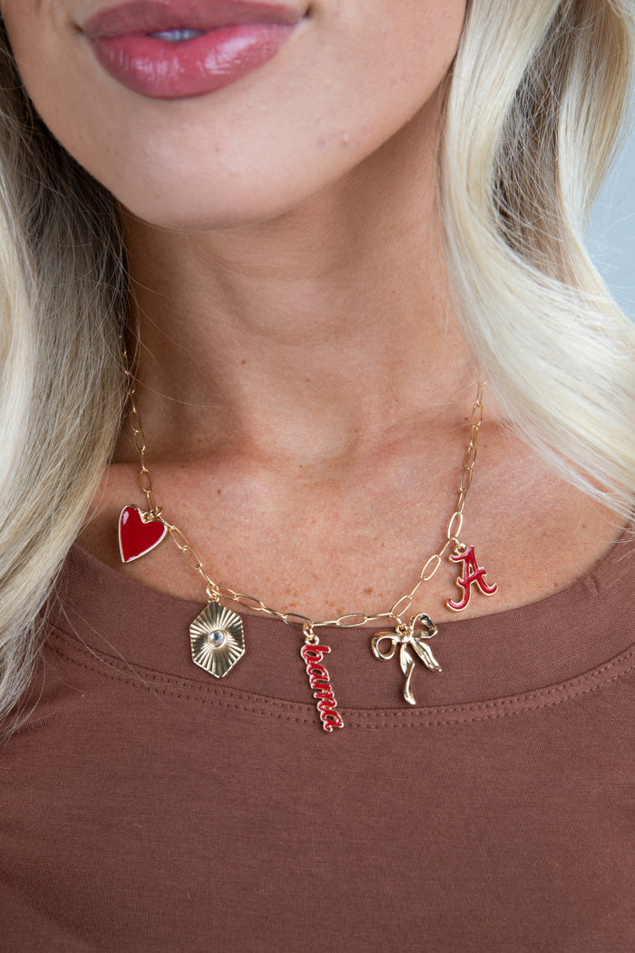 Necklace with various charms including a red heart, star, and letter 'A' worn by a person.