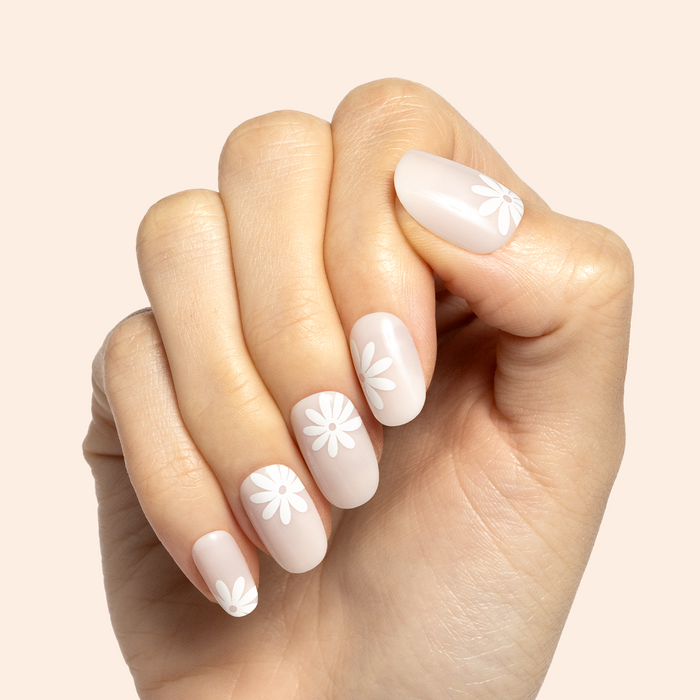 Daisy Pop | Short | Round - Tab Press-On nails in neutral tones with white daisy designs shown on hand with curled fingers