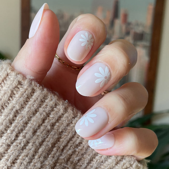 Daisy Pop | Short | Round - Tab Press-On nails with soft neutral base and delicate white daisy accents on hand in cozy sweater