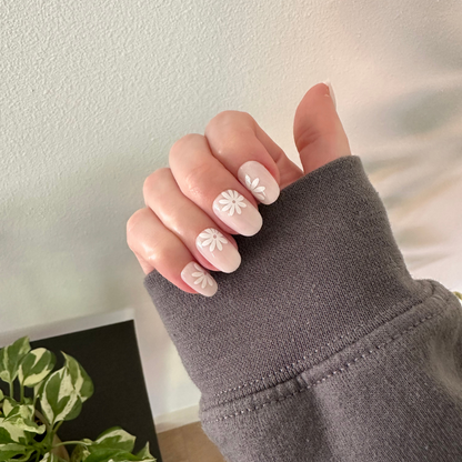 Daisy Pop | Short | Round - Tab Press-On nails with large white daisies on a soft neutral base shown on hand in cozy grey sweater