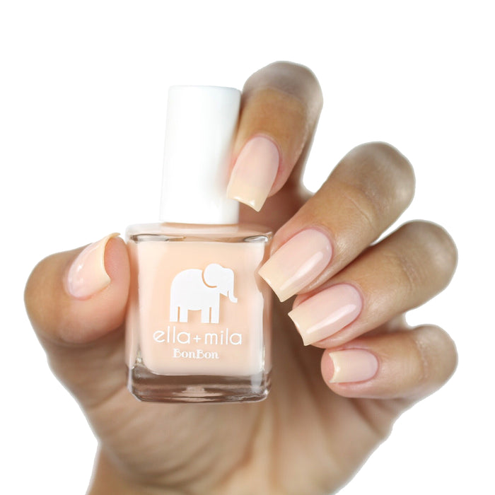 Dessert Island nude shimmer nail polish on a medium skin tone, hand holding the bottle