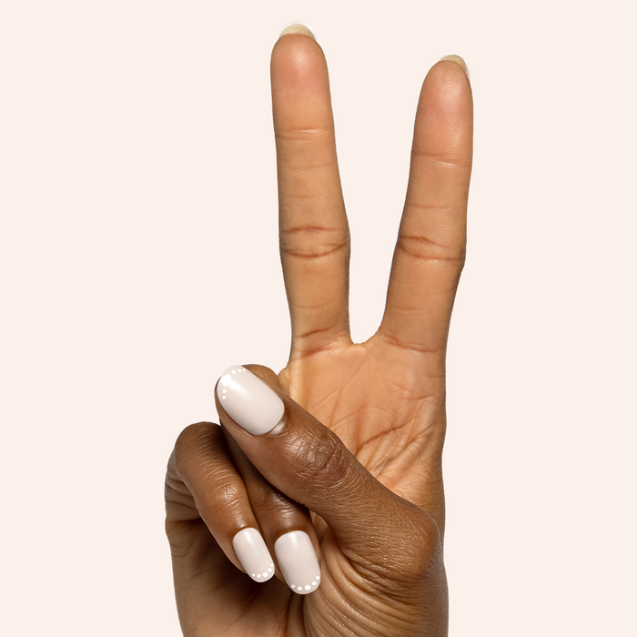 Dotted French | Short | Round - Tab Press-On nails shown on hand making peace sign with white polish and dot detail
