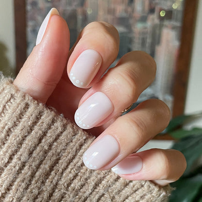 Dotted French | Short | Round - Tab Press-On showing short round nails with subtle white dot French design on hand in cozy sweater
