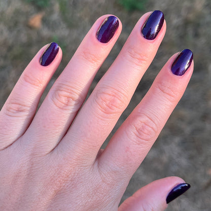 Hand with nails polished in dark shimmering violet Enchanted polish for a smooth, elegant at-home manicure