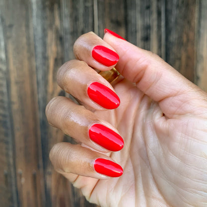 Hand with nails painted in glossy ES polish showing bright cherry red long-lasting manicure on medium skin tone