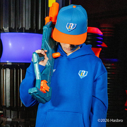 Person wearing a blue BL101 hoodie and cap holding a toy gun with blurred background