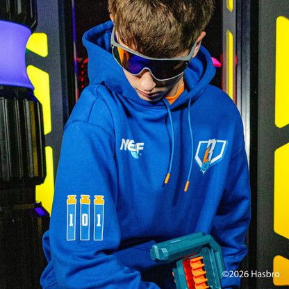 Person wearing a blue hoodie with BL101 X NERF branding, holding a toy gun in front of colorful background