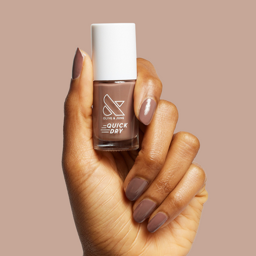 Hand holding Olive and June Fawn quick dry polish with matching neutral brown gel polish manicure