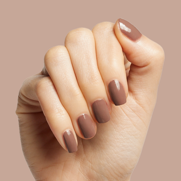 Hand holding nails painted with Fawn gel polish, a soft brown neutral perfect for fall at-home manicure options