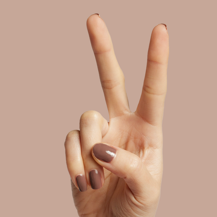Hand showing peace sign with Fawn gel polish in a soft, muted brown shade for effortless at-home manicure looks