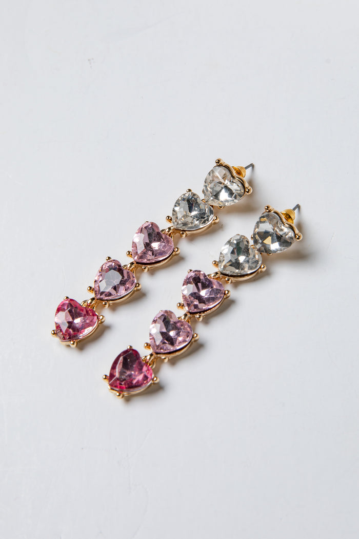 Pair of earrings with pink and clear gemstones on a light gray background