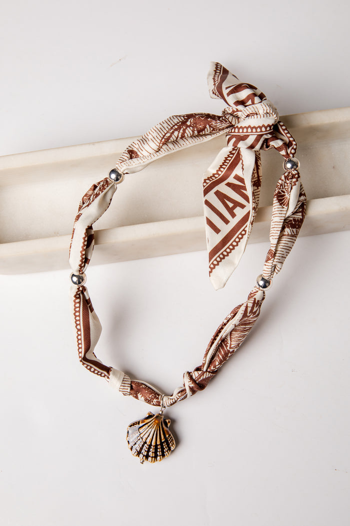 Bracelet with shell charm and patterned band on a white background