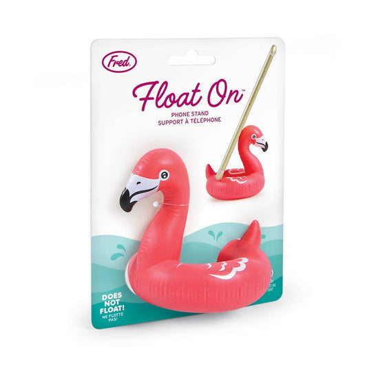 Fred & Friends Float on phone stand shaped like a pink flamingo, holds smartphone upright on a flat surface.