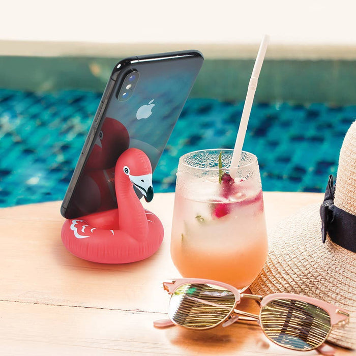 Fred & Friends Float On flamingo phone stand showing a pink flamingo figure holding a phone in its beak on a flat surface.