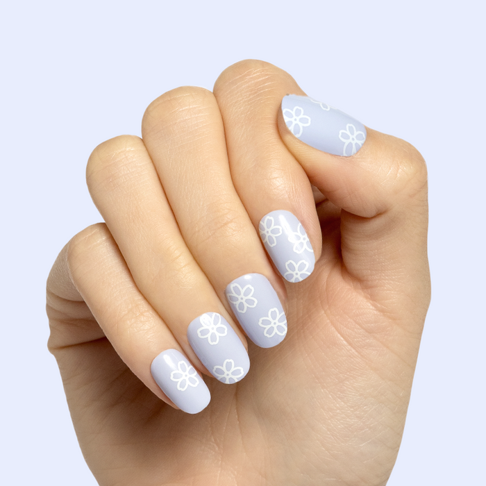 Floral Doodle | Short | Round - Tab Press-On nails with pastel blue base and white flower doodles on hand against light background