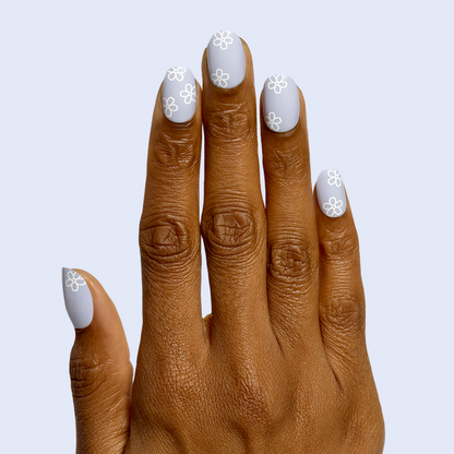 Floral Doodle | Short | Round - Tab Press-On nails with pastel blue base and white flower doodles on hand against soft blue background